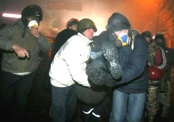 Protesters carry the wounded during the confrontation at Hrushevs’kogo str ~