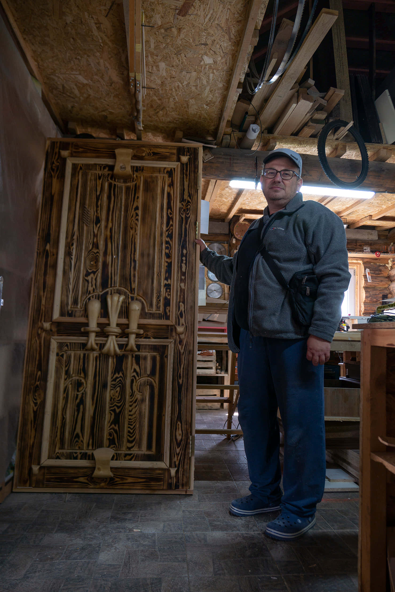Працівник майстерні В’ячеслав показує дерев’яні двері, на якими працювали жителі Анатевки